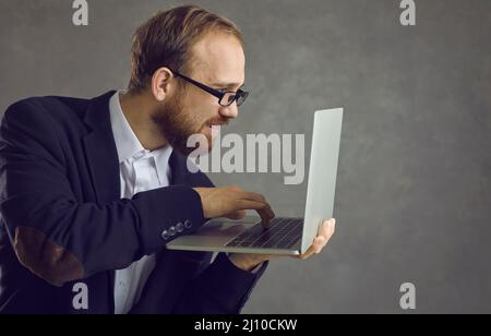 A man is typing on a laptop side view. Stock Photo