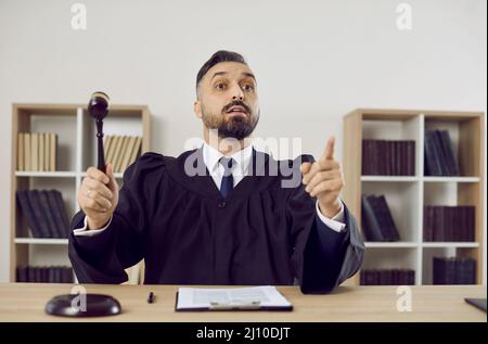 Judge in court of law pronounces his sentence and hits the sound block with his gavel Stock Photo