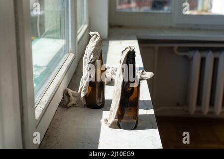 Glass bottle filled with gasoline, a so called Molotov Cocktail, on the window in the house Stock Photo