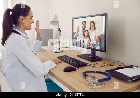 Happy doctor having online consultation with whole family via video call on computer Stock Photo