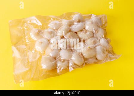 Small flat onions (in Italy called borettane onions) in vacuum packed sealed for sous vide cooking isolated on yellow background Stock Photo