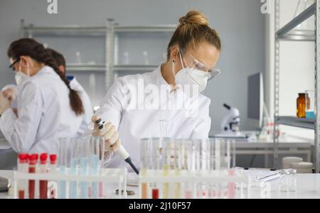 Young scientist using pipette while working in modern pharma or biotech laboratory Stock Photo