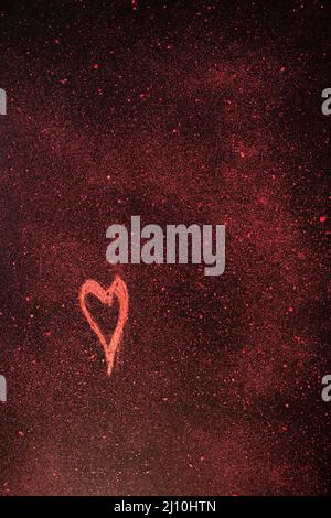 Red heart shape drawn with red chalk  on black background with red small pieces of chalk Stock Photo