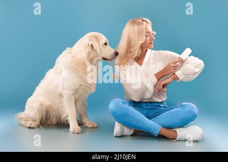 Woman cleaning her clothes from dog fur with adhesive roller Stock Photo