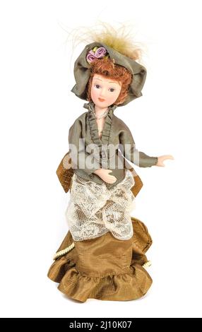 Amazing realistic porcelain toy Doll dressed in a dress in the style of the 19th century on a white background with selective focus Stock Photo