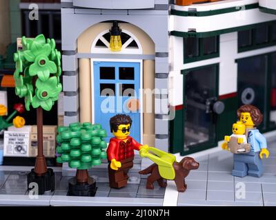 Tambov, Russian Federation - January 08, 2022 A Lego visually impaired man minifigure with a guide dog walking on a city street with a Lego mother wit Stock Photo
