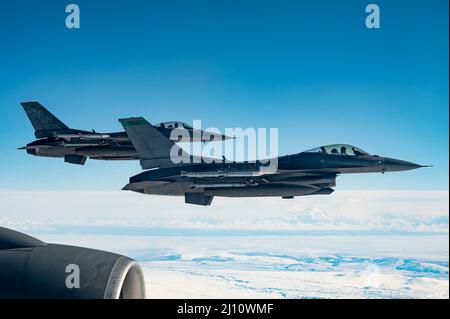 Anchorage, United States. 16 March, 2022. U.S. Air Force F-16 Fighting Falcon jet fighters, assigned to the 180th Fighter Wing, pull away after refueling from a  KC-135R Stratotanker during Northern Command Exercise Arctic Edge 2022, March 16, 2022 over Alaska. The Northern Command exercise is part of recent military moves to deter Russian involvement in Ukraine.  Credit: SSgt. Taylor Crul/U.S. Air Force/Alamy Live News Stock Photo