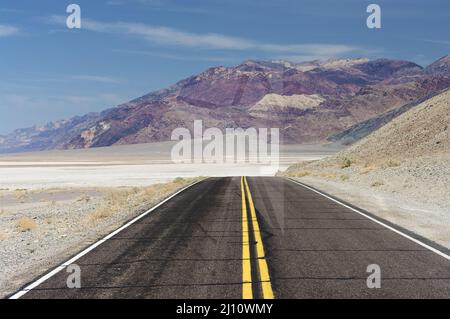 Road in Death Valley National Park in California shown near Badwater, the lowest point below sea level in North America. Stock Photo