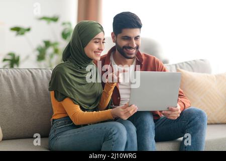 Middle Eastern Couple Using Laptop Computer Sitting At Home Stock Photo