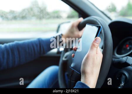 Male hands with phone. Man in car is using smartphone. Stock Photo