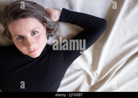 35 woman smiling at camera. Profile view of mature woman in black casuals looking happy Stock Photo