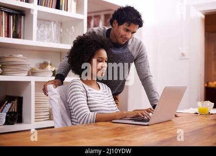 Your blog is looking great honey. Shot of a young couple using a laptop together at home. Stock Photo