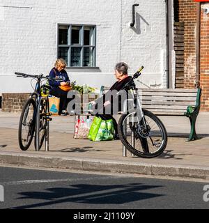 Epsom Surrey London UK, March 21 2022,Two Senior Or Elderly Women With Shopping Bags Relaxing On Wooden Benches Stock Photo