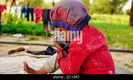Cute Indian kid studying, in garden at home due to Corona pandemic. Stock Photo