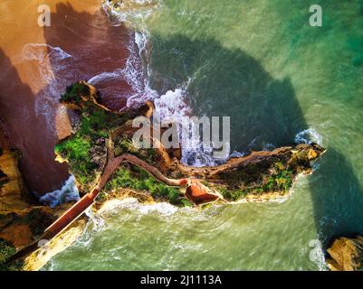 Aerial shot Praia dos Estudantes or Beach of Students with group of rock formations yellow-golden cliffs along limestone coastline, Lagos town Stock Photo