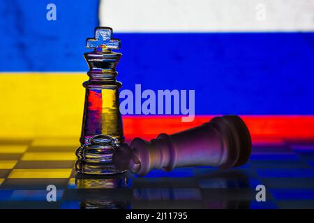 Fallen chess king as a metaphor for fall from power ukraine invasion ukrainian and russian flag background copy space Stock Photo