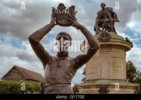 A statue of William Shakespeare's Prince Hal lifts a crown above his head watched over by a statue of the Bard himself. Stratford Upon Avon, England. Stock Photo