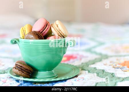 Close up of french macaron cookies in a vintage green bowl on a bed. Stock Photo