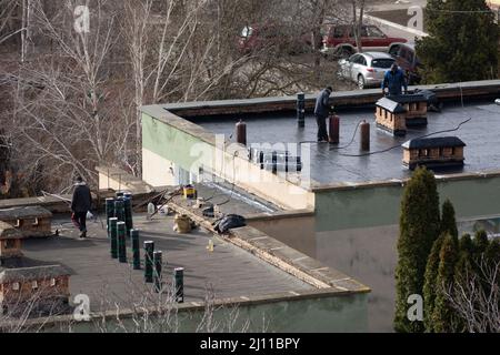 Tiraspol, Moldova - March 21, 2022: Cover the roof with bitumen. Workers cover the roof with bitumen of a kindergarten building. Stock Photo