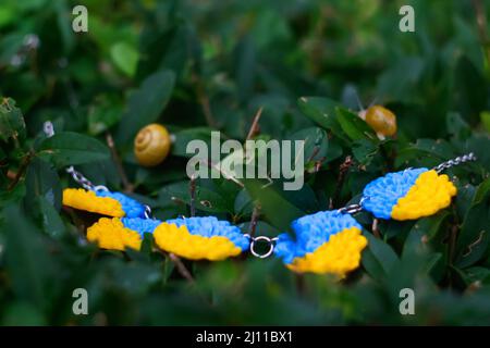 National ukrainian necklace decoration. Flag symbol of Ukraine. Snails on bushes garden outside. Victory of war. Patriot. Activism. Freedom. War Stock Photo