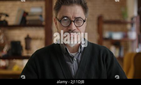 Happy bearded older man at home wearing glasses looking at camera, smiling. Portrait of mature age, middle age, mid adult man in 50s. Stock Photo