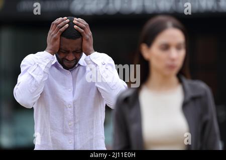 Front view portrait of an interracial couple breaking up in the street Stock Photo