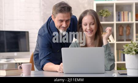 Business people working in office with laptop computer. Happy couple working from home at desk. Talking, meeting, cooperation, entrepreneurs, advisor. Stock Photo