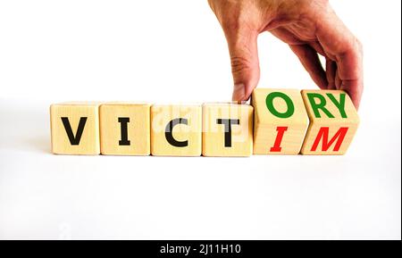 From victim to victory symbol. Businessman turns wooden cubes and changes concept words Victim to Victory. Beautiful white background. Business suppor Stock Photo
