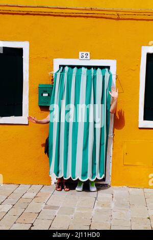 Shot of two persons hiding behind curtain in yellow motel, funny act Stock Photo