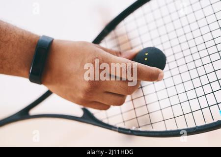 A good game starts with a good serve. Cropped shot of a man serving a ball with a racket during a game of squash. Stock Photo