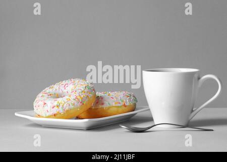 Breakfast for loved ones - freshly brewed coffee in a cup and 2 colorful donuts Stock Photo