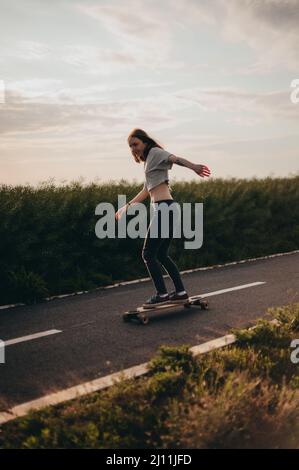 woman carving on a longboard with arms outstretched and enjoys a free ride. Sunny day , poster, longboard day Stock Photo