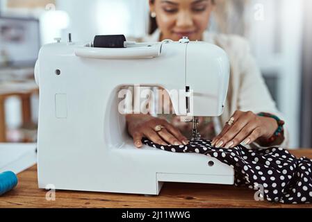 Making a few alterations. Cropped shot of a young fashion designer using a sewing machine in her workshop. Stock Photo