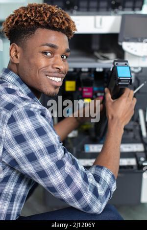 worker holds ink cartridge to put into printer Stock Photo