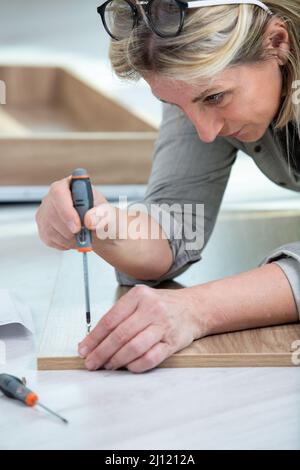 woman assembling wooden furniture using screwdriver Stock Photo