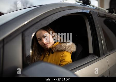 Young woman with Down syndrome driving a car and looking at camera. Stock Photo
