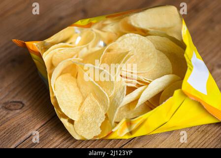 Potato chips on wooden background, Potato chips is snack in bag package wrapped in plastic ready to eat and fat food or junk food Stock Photo