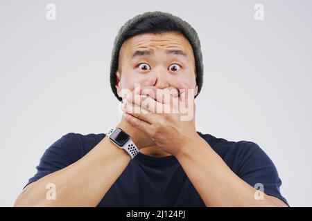 How did that happen. Studio shot of a young man looking shocked against a grey background. Stock Photo