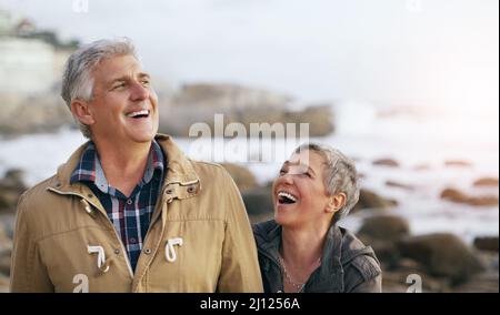 Weve always shared the best laughs together. Shot of a beautiful elderly couple taking a walk at the beach. Stock Photo