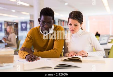 People reading and making notes while preparing for exam in library Stock Photo