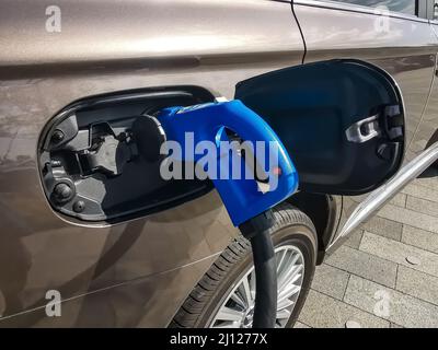 Electric car is refueled. Picture shows an electro connector and car in detail with the tank cap open Stock Photo