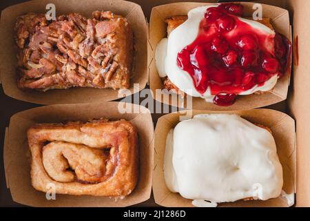 Pecan, Cream Cheese frosted, Cherry frosted, and Original cinnamon rolls close up, flat lay Stock Photo