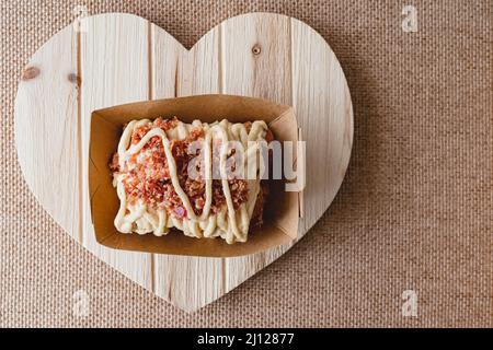 Maple Bacon cinnamon roll close up on a wooden heart-shaped board, flat lay with copy space Stock Photo