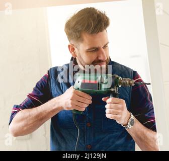 Hes the man for the job. Shot of a handsome young handyman using an electric drill for some DIY. Stock Photo