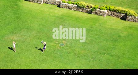 A woman photographs a man doing a handstand on an expanse of grass at Santa Barbara, California Stock Photo