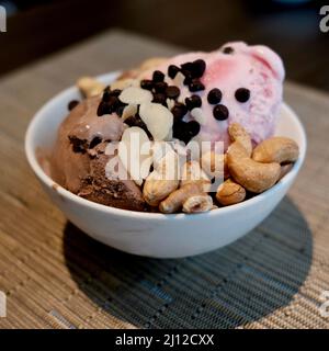 Bowl of Vanilla Chocolate and Strawberry Ice Cream with Almond and Cashew nuts and Chocolate Chips at all you can eat Buffet in Bangkok Thailand Stock Photo