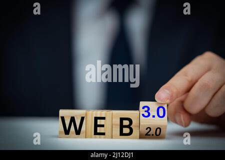Businessman turns a wooden cube and changes words WEB 2.0 to WEB 3.0. Business, technology and WEB 3.0 concept. Stock Photo