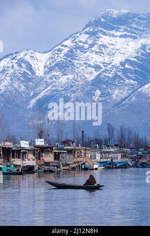 March 22, 2022, Srinagar, Jammu and Kashmir, India: A boatwoman rows her boat in the Dal Lake with snow clad mountains in the back drop in Srinagar, Indian-Administered Kashmir. (Credit Image: © Adil Abbas/ZUMA Press Wire) Stock Photo