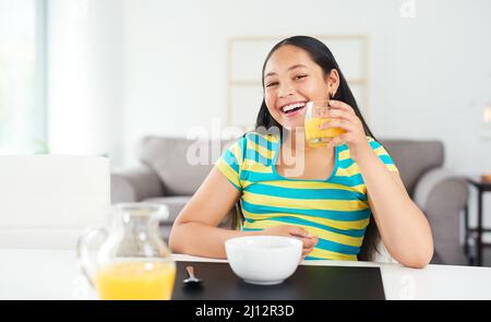 Get the day going with an awesome breakfast. Portrait of a happy young girl enjoying a healthy breakfast at home. Stock Photo