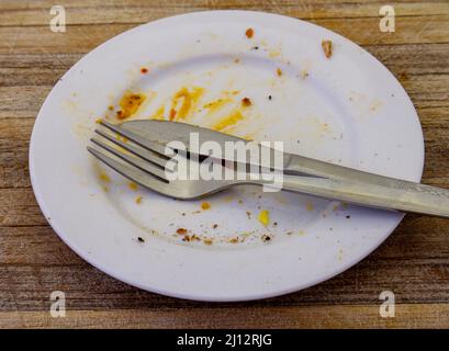 An empty dinner plate after a meal isolated on a wood surface Stock Photo